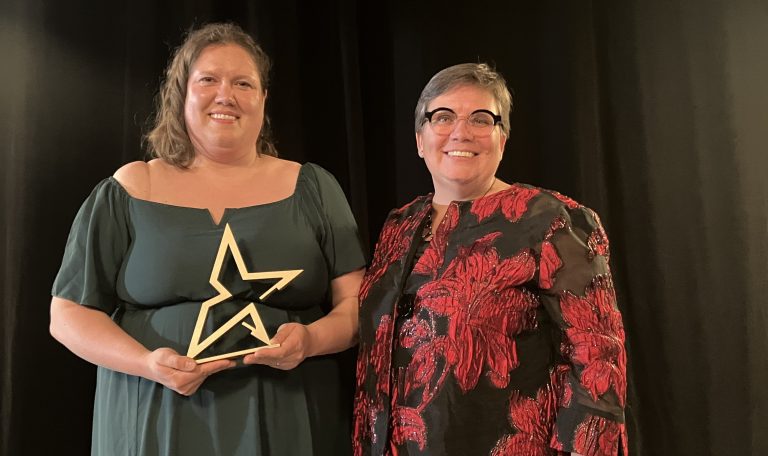 deux femme dont une avec un trophée sur fond noir lors d'un gala